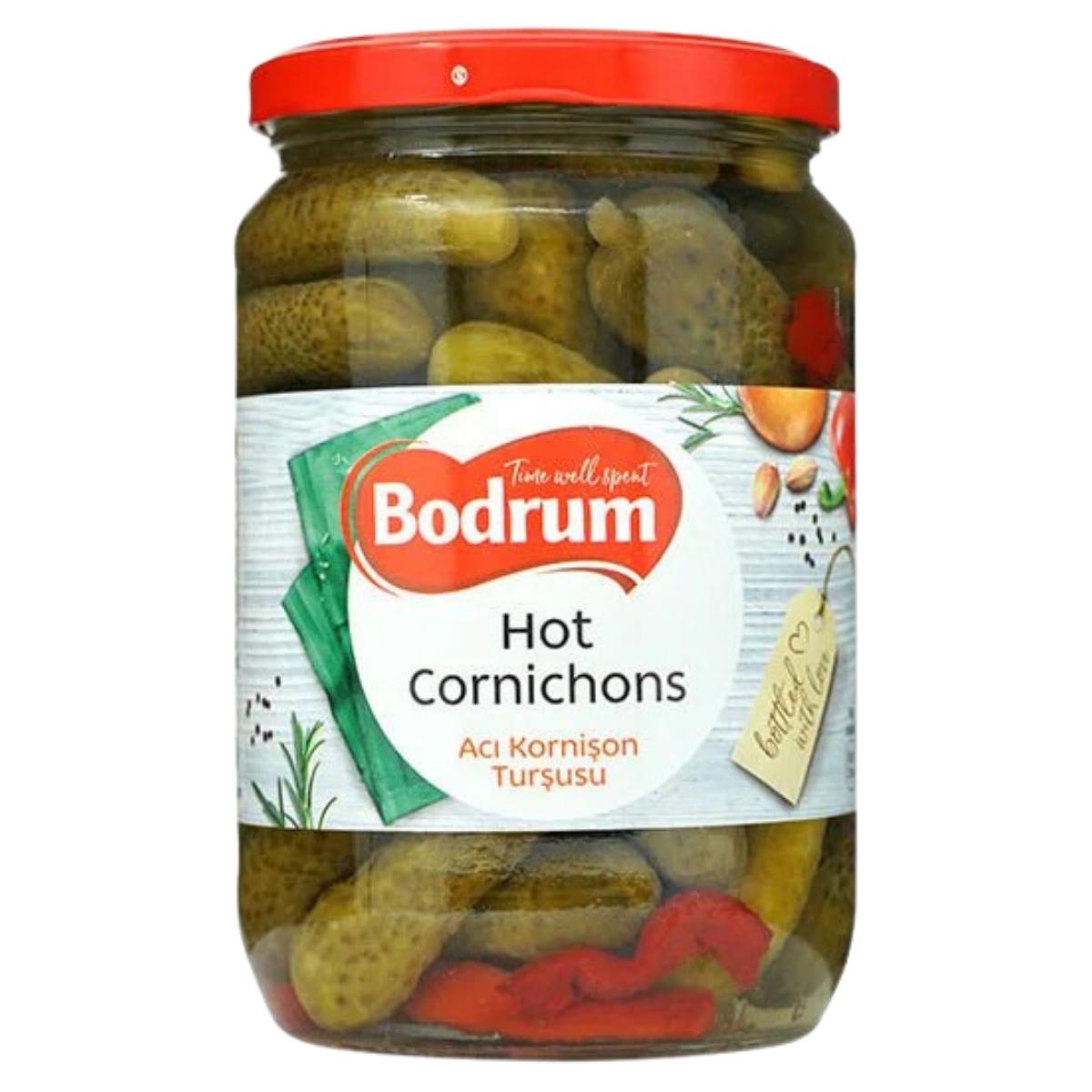 A 680g jar of Bodrum Crunchy Cocktail Cornichons in Vinegar with Hot Pepper, featuring pickles and red peppers inside, with a red lid. A 680g jar of Bodrum Crunchy Cocktail Cornichons in Vinegar with Hot Pepper, featuring pickles and red peppers inside, with a red lid.