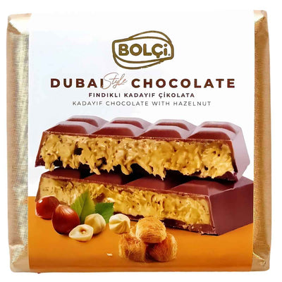 A 100g package of Bolci Dubai Kadayif Chocolate with Hazelnut, showing the chocolate bar filled with creamy filling and whole hazelnuts in front of the Bolci packaging.