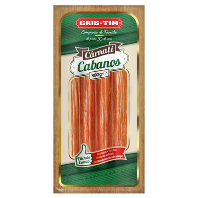 A package of Cris-Tim Camati Cabanos, featuring sticks of meat in a clear windowed package with green and red branding on a light wood background.