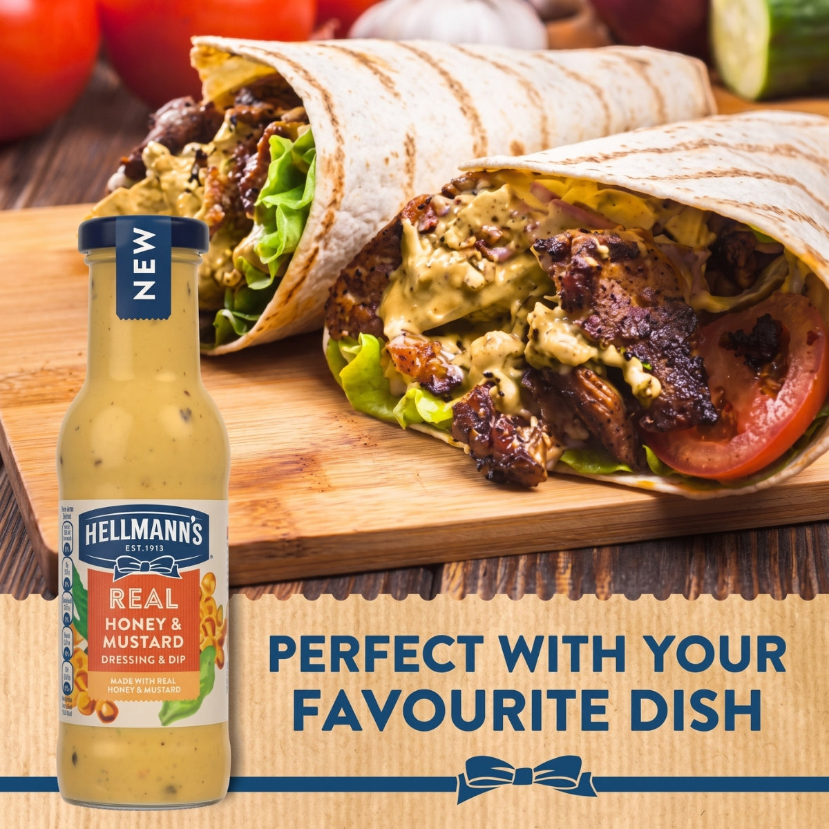 A 250ml bottle of Hellmann’s Real Honey & Mustard Salad Dressing & Dip Sauce is displayed beside grilled wraps filled with lettuce, tomato, and sauce, arranged on a wooden table with fresh vegetables in the background.