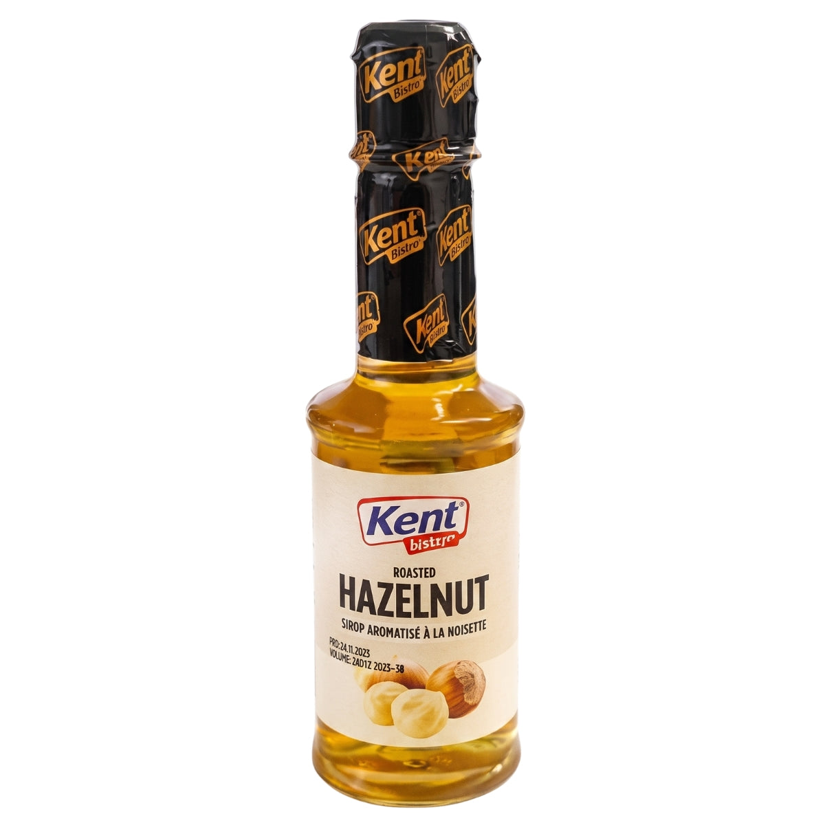 A bottle of Kent Roasted Hazelnut syrup, featuring a clear glass bottle filled with golden-brown liquid, a cream-colored label with hazelnut illustrations, and a black foil neck seal with gold branding.