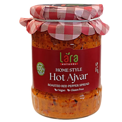 A 550g glass jar of Lara Home Style Hot Ajvar, a vegan and gluten-free roasted red pepper spread, features a red and white checkered lid.