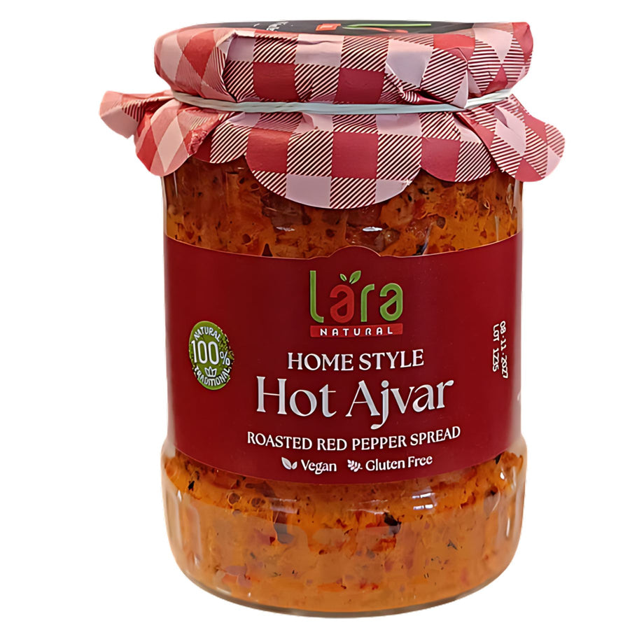 A 550g glass jar of Lara Home Style Hot Ajvar, a vegan and gluten-free roasted red pepper spread, features a red and white checkered lid.