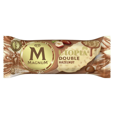 The Magnum Ice Cream Stick Utopia Double Hazelnut - 70g features eye-catching packaging with the iconic golden "M" logo, enticing chocolate and hazelnut images on a rich brown background, promising a crispy coating and double hazelnut flavor.