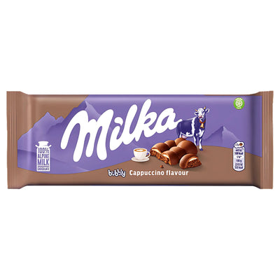 Milka - Bubbly Cappuccino Chocolate Bar 100g blends smooth milk chocolate with a unique cappuccino flavor in purple packaging, featuring Milka’s cow, mountains, a milk icon, and a cappuccino cup illustration.