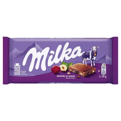 A Milka - Chocolate Bar With Raisins & Nuts - 90g wrapper featuring a purple background, a cow illustration, and a cross-section of chocolate showing raisins and hazelnuts.