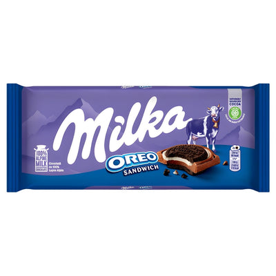 The Milka - Oreo Sandwich Chocolate Bar (92g) by Milka comes in purple packaging with a cow, combining Alpine milk chocolate, Oreo biscuits, cocoa biscuits with vanilla flavor filling, and product details.