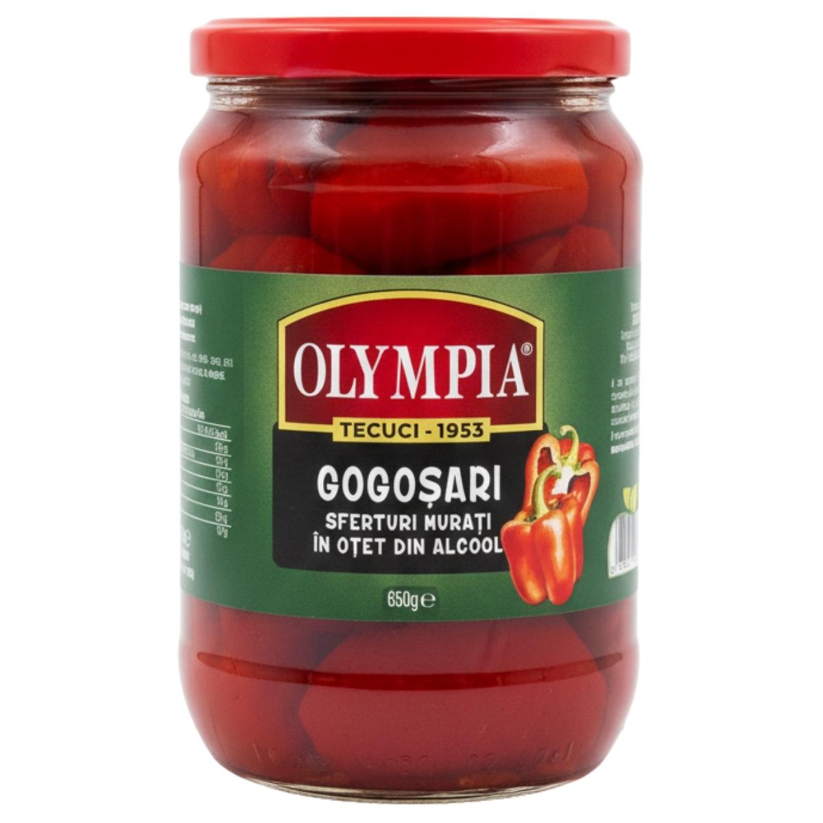 Olympia Pickled Red Peppers in Vinegar (650g) come in a jar with a red lid and green label featuring peppers. Labeled in Romanian, they’re ideal for antipasti or adding zest to Mediterranean dishes.