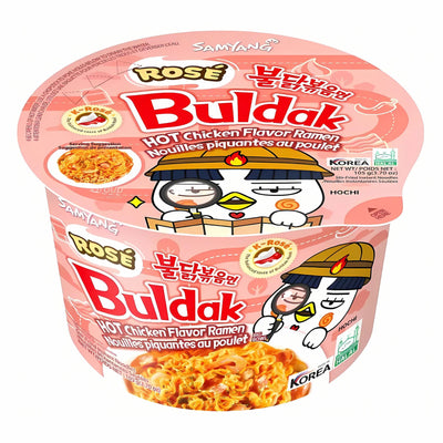 A 105g cup of Samyang - Buldak Rose (Carbonara Style) Hot Chicken Flavour Ramen with cartoon chicken characters on a pink lid and packaging, featuring both Korean and English text.