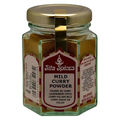 A 30g hexagonal glass jar with a gold lid, filled with Sita Spices - Mild Curry Powder. The label displays the product name and description in several languages, celebrating aromatic spices in every blend.