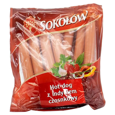 A sealed pack of Sokolow Garlic Franks (1.119kg), with Polish text and images of herbs and vegetables on the label, offers classic cooked poultry and pork flavors enhanced with turkey and garlic in every bite.