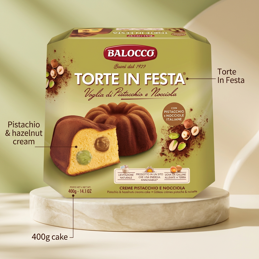 A Balocco Torte In Festa Pistachio & Hazelnut Cream Cake 400g ring cake on a stone pedestal, with a slice showing green pistachio and brown hazelnut cream filling.