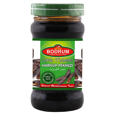 A 380g jar of Bodrum Carob Molasses with a green lid and a label featuring the product name in English, Turkish, and Arabic, plus images of carob pods.