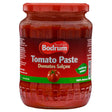 A 700g glass jar of Bodrum Tomato Paste with a red label and lid, featuring "Domates Salçası," a tomato image, "nothing added," "100% natural," and ideal as vegan tomato paste.