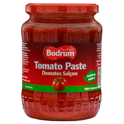 A 700g glass jar of Bodrum Tomato Paste with a red label and lid, featuring "Domates Salçası," a tomato image, "nothing added," "100% natural," and ideal as vegan tomato paste.