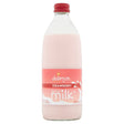 A 500ml bottle of Delamere Dairy Strawberry Flavour Milk, made with semi-skimmed milk and featuring a red cap with a pink label.