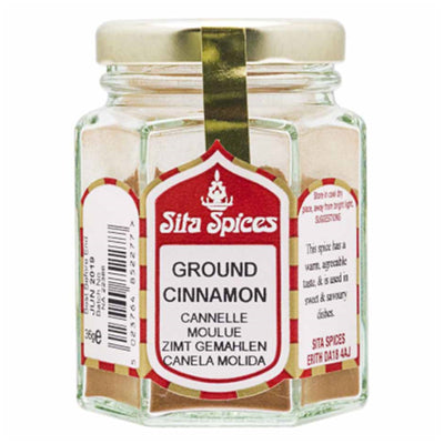 A 32g glass jar of Sita Spices Ground Cinnamon with a gold lid and a multilingual label displaying product details.